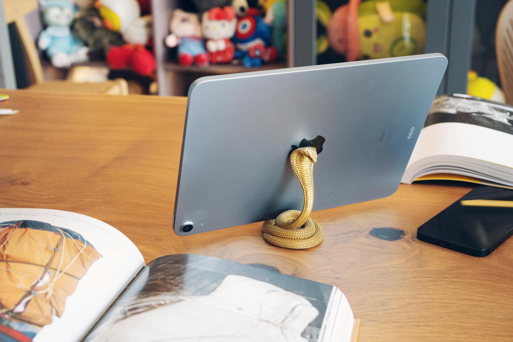The iPad Man - Helping Seniors with Apple Products Elegant Snake Shaped Gold Tablet Stand On A Wooden Table With Books And Plush Toys In Background. 15979709 2048x1365